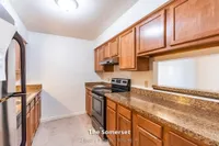 Charming kitchen in The Somerset apartment, featuring sleek granite countertops, rich wooden cabinetry, and modern appliances in a cozy 970 sq. ft. space.