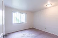 Bright bedroom in The Somerset apartment, featuring plush carpeting and a large window allowing ample natural light. Ideal 2 Bed, 1 Bath living space, measuring 970 sq. ft.
