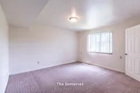 Spacious bedroom in The Somerset apartment, showcasing ample natural light, cozy carpeting, and modern design in a 2 bed, 1 bath layout of 970 sq. ft.