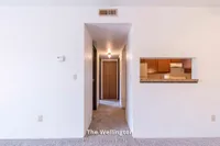Inviting apartment entryway leading to a cozy kitchen with warm wooden cabinetry, part of The Wellington's 2 bed, 1 bath, 900 sq. ft. layout.