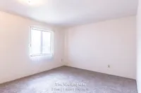 Bright and spacious room with soft carpeting and a large window, part of The Wellington's 2 Bed, 1 Bath, 900 sq. ft. offering.