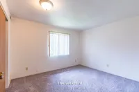 Bright and cozy empty bedroom in The Wexford, featuring soft carpet and natural light, part of a 1 bed, 1 bath, 690 sq ft apartment.