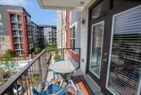 Charming balcony view of modern apartment complex with outdoor pool, colorful patio furniture, and elegant glass doors.