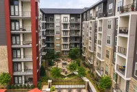 Modern apartment complex with multi-story buildings featuring elegant balconies and a lush central courtyard for relaxation and socializing.