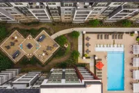 Aerial view of a luxurious apartment complex featuring a central courtyard with stylish seating, lush landscaping, and a sparkling swimming pool, ideal for leisure and relaxation.