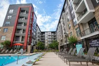 Modern apartment complex featuring stylish architecture, a refreshing pool, and sun loungers, perfect for relaxation and upscale living.