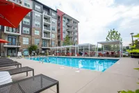Modern apartment complex with a luxurious outdoor pool surrounded by cozy lounge chairs and private cabanas, perfect for relaxation and leisure.