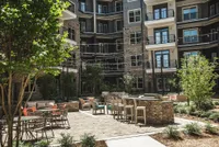 Charming apartment courtyard with stylish seating, lush greenery, and ambient string lights perfect for relaxation and entertainment.