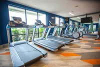 Modern fitness center with state-of-the-art treadmills and expansive windows showcasing lush greenery.
