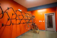 Vibrant communal bike storage room with secure wall-mounted racks and a stylish orange backdrop.