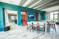 Vibrant, modern communal space with teal accent walls, stylish seating, and an elegant marble-tiled floor, perfect for social gatherings and relaxation.