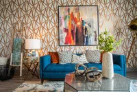 Contemporary living room with a stylish blue sofa, abstract art piece, and geometric wallpaper, accented by modern decor and lush greenery.