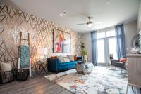 Vibrant living room with stylish geometric wall design, modern blue sofa, and chic decor accents.