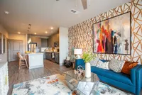 Contemporary open-concept living space featuring a stylish kitchen, vibrant artwork, and a cozy seating area with a modern geometric coffee table.