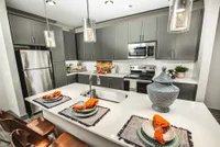 Modern kitchen with sleek dark cabinetry, stainless steel appliances, and a stylish island adorned with elegant table settings and contemporary decor.