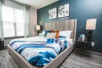 Inviting bedroom with modern design featuring a large bed, stylish linens, and contemporary decor, accented by a calming blue wall.