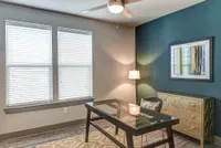 Bright and inviting home office with modern glass desk, stylish decor, and ample natural light.
