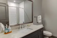 Elegant bathroom featuring a sleek vanity with a large mirror, pristine white countertops, and a modern bathtub with subway tile surround.