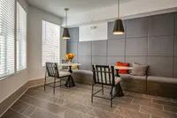 Elegant apartment lounge area with modern seating, ambient pendant lighting, and a stylish gray tiled floor.