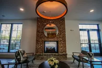 Modern lounge area featuring a stylish brick fireplace, elegant round mirror, and contemporary seating under warm lighting.