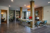 Chic and inviting communal area featuring modern seating, a brick fireplace, and stylish decor with geometric wall art and elegant lighting.