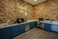 Chic communal workspace with modern stone accent wall, coffee station, and sleek office amenities.