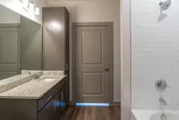 Modern bathroom with elegant granite countertop, sleek cabinetry, and tiled shower for a luxurious touch.