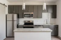 Modern kitchen with sleek stainless steel appliances, elegant dark cabinets, and a spacious granite countertop island, offering a blend of style and functionality.