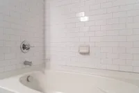 Elegant bathroom showcasing a pristine white-tiled wall and a modern bathtub, highlighting luxury and comfort.