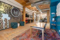 Contemporary office space with vibrant wall art, cozy seating, and wooden accents featuring an industrial design.