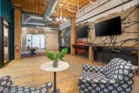 Trendy loft-style lounge with industrial design, featuring cozy seating, vibrant artwork, and rustic wooden floors.
