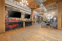 Trendy loft-style space with exposed beams, vibrant abstract wall art, modern lighting, and stylish seating area.