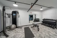 Modern fitness room with state-of-the-art gym equipment, free weights, and a mirrored wall for an enhanced workout experience.