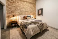 Cozy bedroom with exposed brick wall, soft lighting, and stylish modern decor.