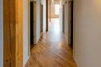 Inviting hallway featuring warm wooden floors, leading to spacious, well-lit rooms.
