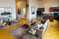 Chic open-concept living area with elegant hardwood floors, modern kitchen, and cozy seating arrangement.