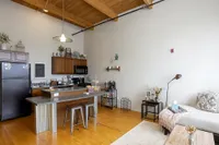 Chic open-concept living area with a cozy kitchen, featuring wooden beams and modern decor.