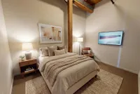 Cozy bedroom with warm lighting, featuring a comfortable bed, stylish artwork, and modern decor in a chic apartment setting.
