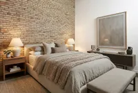 Cozy and stylish bedroom features a textured brick wall, plush bedding, ambient lighting, and elegant decor for a serene atmosphere.
