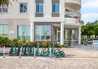 Modern apartment building entrance with stylish architecture, enhanced by a row of vibrant electric scooters for an eco-friendly lifestyle.