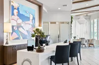 Elegant and modern office space with stylish decor, featuring a white reception desk, abstract artwork, and cozy seating area with natural lighting.