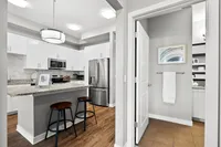 Elegant modern kitchen featuring sleek white cabinetry, granite countertops, stainless steel appliances, and a cozy breakfast bar with chic bar stools.