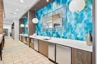 Modern kitchen area with elegant wood cabinets, a vibrant teal backsplash, and sleek stainless steel appliances, creating a contemporary and inviting ambiance.