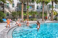 Vibrant apartment community poolside scene with happy residents enjoying sunny day, surrounded by lush palm trees and modern balconies.