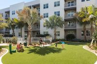 Vibrant apartment complex with tropical landscaping, a spacious courtyard, and residents enjoying outdoor activities.