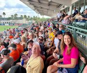 Vibrant baseball game crowd enjoying a sunny day at the stadium, surrounded by palm trees and a lively atmosphere.