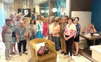 Cheerful gathering of smiling women in a modern, inviting lounge with chic decor, cozy seating, and ambient lighting.