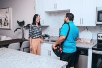 Modern kitchen setting with granite countertops and elegant cabinetry, highlighting a friendly interaction between two people.