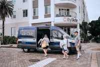 Welcoming entrance of CitySide Residences with guests boarding a stylish club van, surrounded by lush greenery.