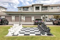 Contemporary apartment complex with an eye-catching giant outdoor chess set, offering unique recreational space and covered parking.